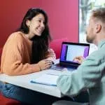 un homme et une femme assis à une table avec un ordinateur portable