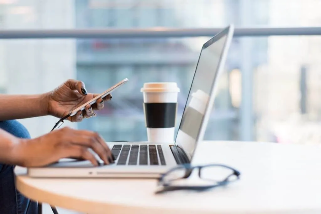 personne en téletravail utilisant un smartphone et un MacBook