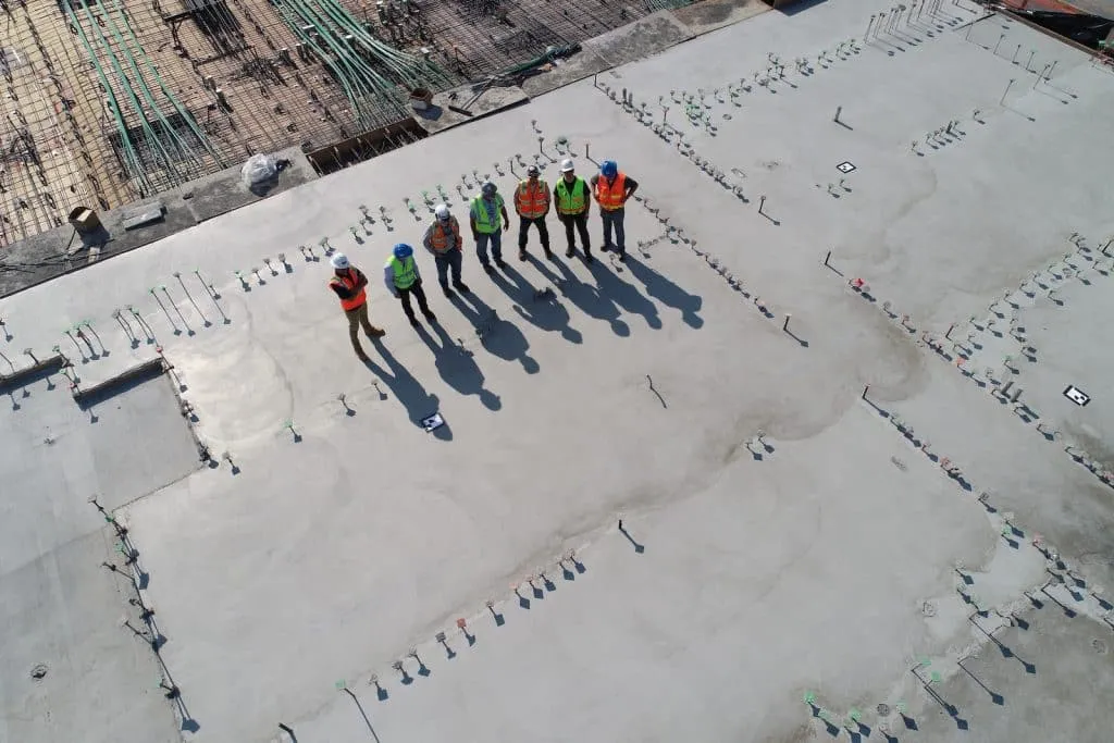 sept travailleurs de la construction debout sur un terrain blanc travaillant en interim à la semaine